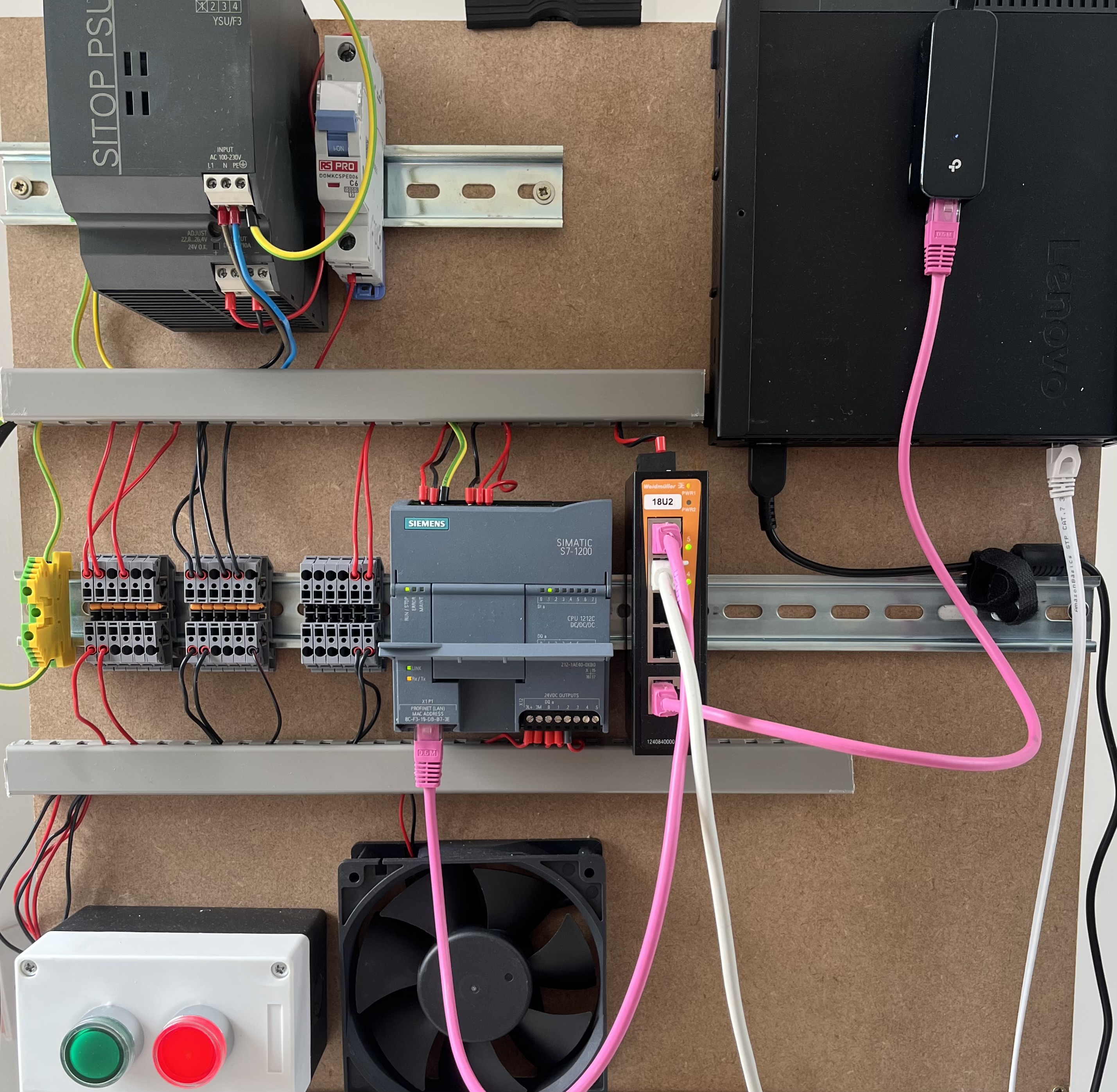 The completed OT lab on a plywood board, showing the Siemens S7-1200 PLC, power supply, ethernet switch, buttons and fan
